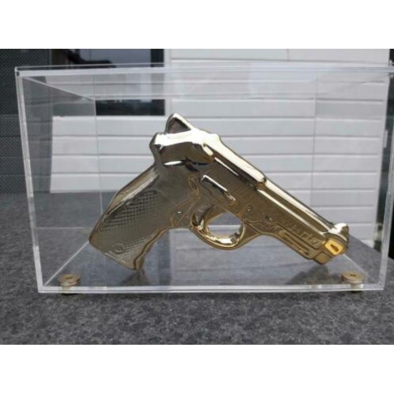 Gouden namaak design pistool / revolver in glazen vitrine.